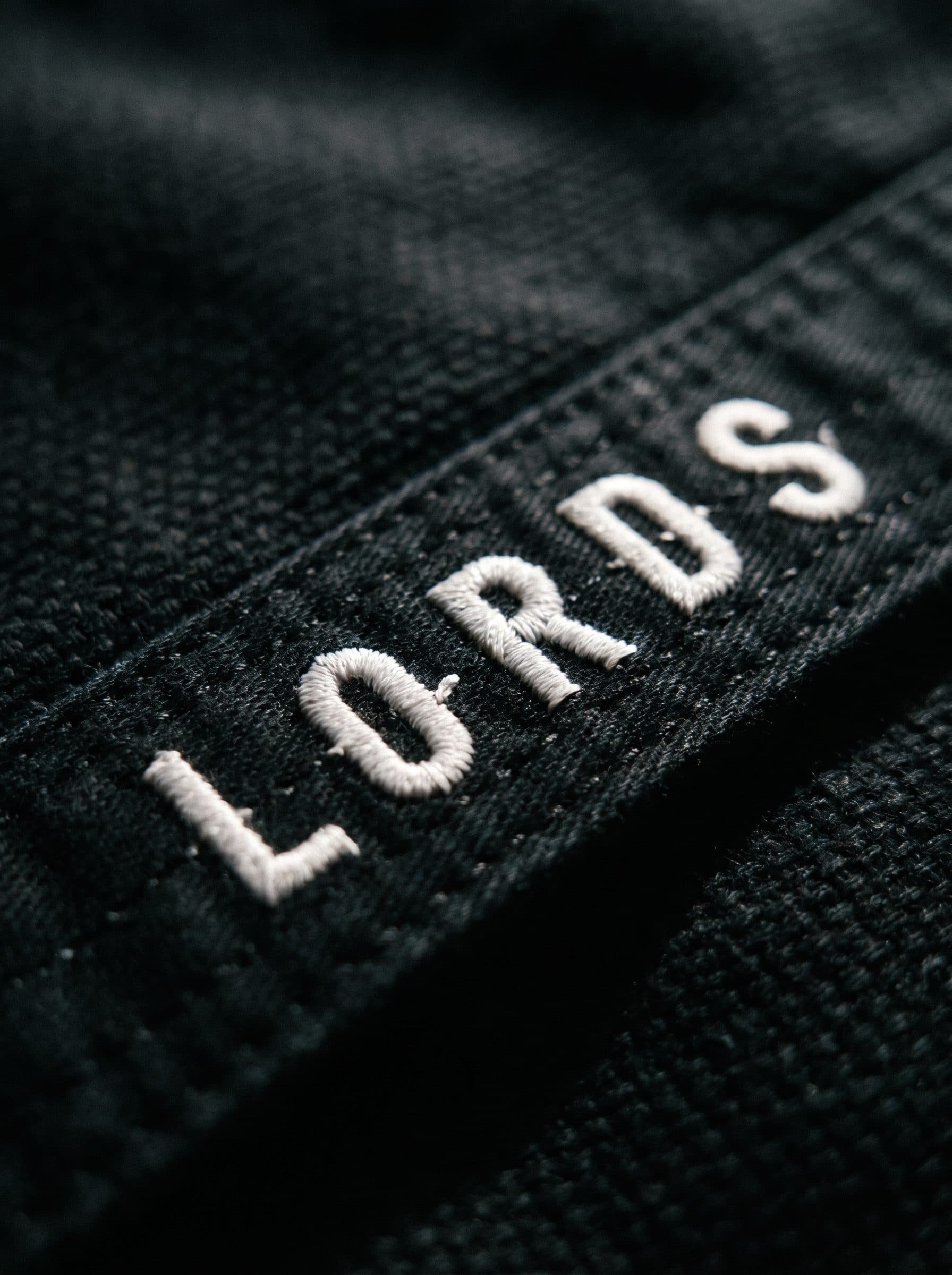 Bordado LORDS em linha branca sobre tecido preto